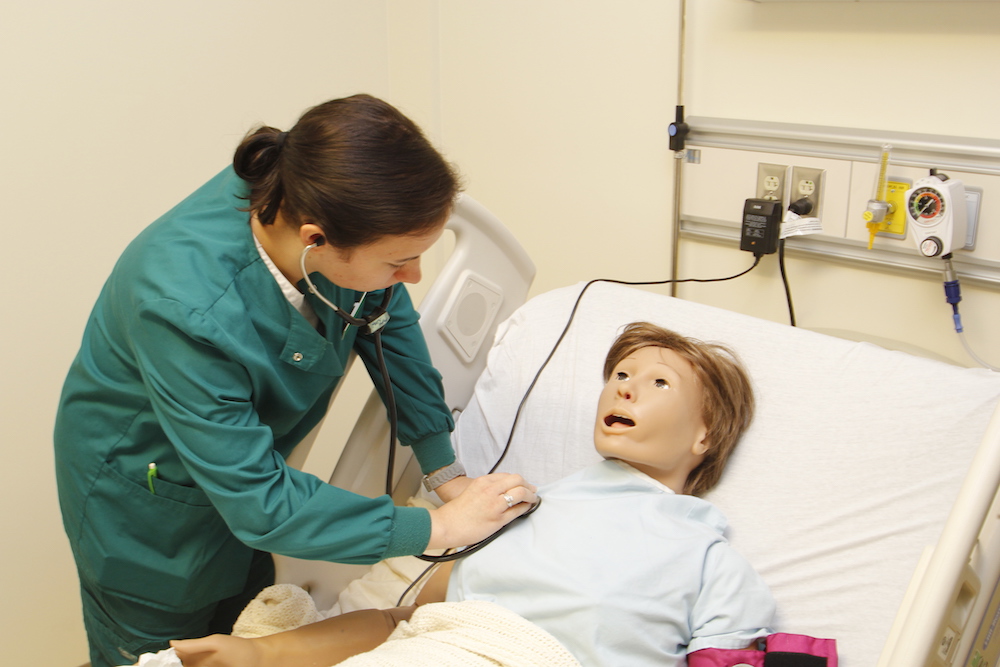 A female nursing 첥 works with an adult patient simulation